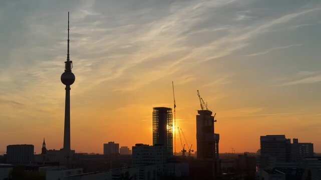 Urban development and city growth in Berlin, Germany: Aerial view of TV tower and high-rise buildings with cranes among them at sunset