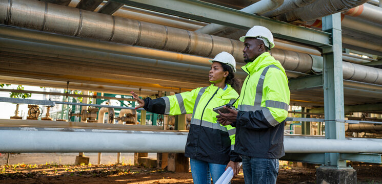 Young mechanical engineer holding blueprint drawing to checking and inspection gas pipeline system new construction project of industrial.