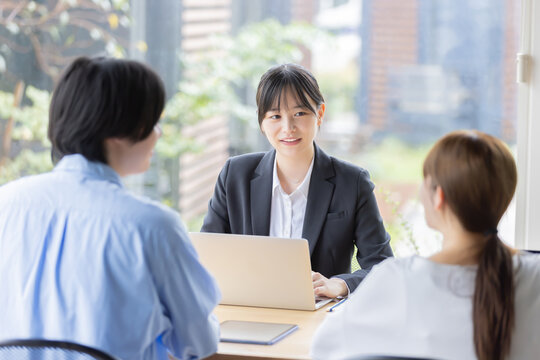 ノートパソコンを使い男女2人と打ち合わせをする日本人女性