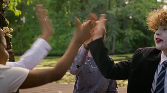Multiethnic teenagers in Halloween makeup giving high fives together outdoors. Clip works well for autumn holiday marketing, seasonal youth campaigns and festive video projects