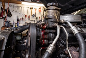 Fototapeta premium Car engine power steering fluid leak dripping red oil in auto repair shop