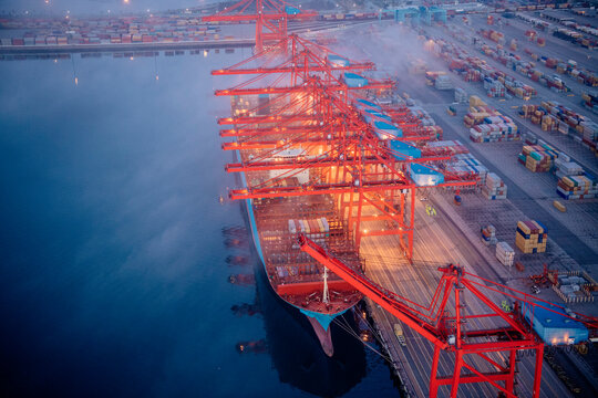 Container ship loaded by red cranes