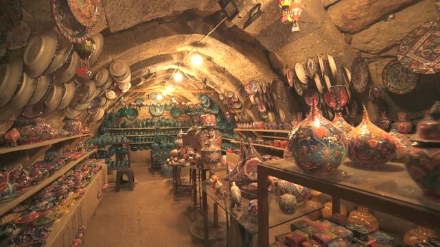 Shelves packed with handmade ceramics fill a cave shop interior with warm artisan character.
