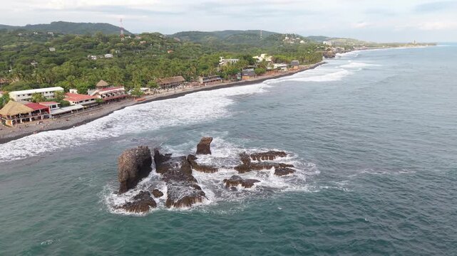 Aerial view of black sand beach and coastal buildings, El Salvador.