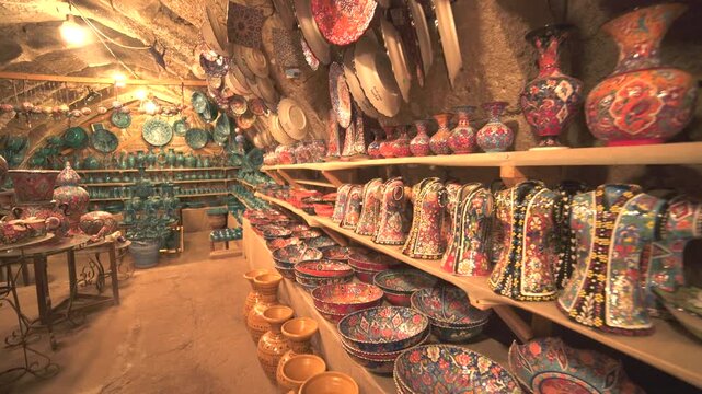 Shelves packed with handmade ceramics fill a cave shop interior with warm artisan character.