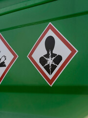 A health hazard pictogram in red and white stands out against the green steel wall of a storage container. © Victor