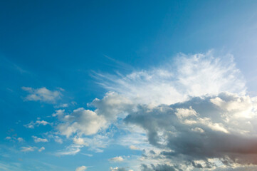 Fototapeta premium Blue evening sky landscape with soft white sunset clouds, wispy cloud layers and bright open space in a peaceful atmosphere