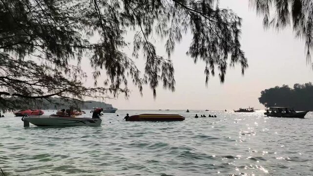 Jakarta, Indonesia - April 24, 2026: Row of fishing boats anchored at shore under coastal trees