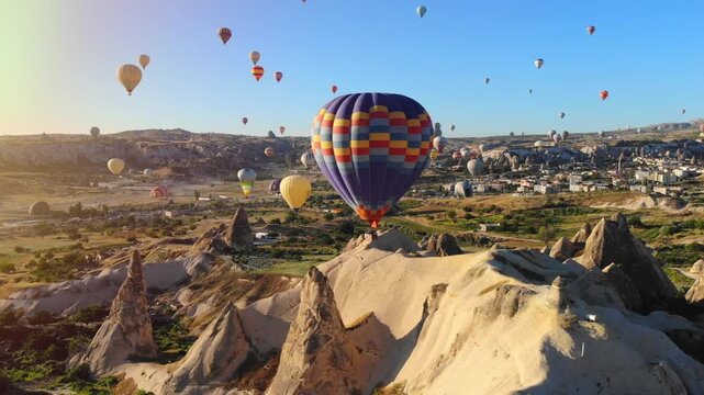 Hot air balloons fill Cappadocia skies above fairy chimneys during a glowing sunrise.