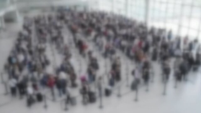 Blurred crowd of travellers in a long winding security queue at a bright airport