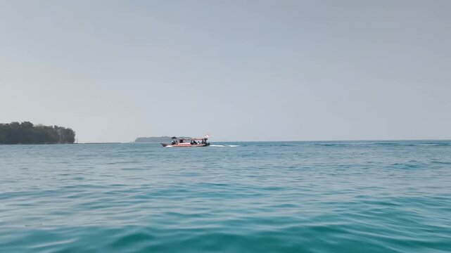 Wide view of calm blue sea surface with tropical islands on horizon