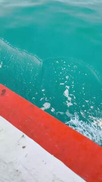 Jakarta, Indonesia - April 24, 2026: Sea water foam broken by moving orange motorized boat