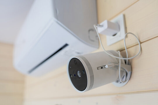 A wall-mounted projector hangs on the wall next to the air conditioner in the meeting room. Portable home theater.