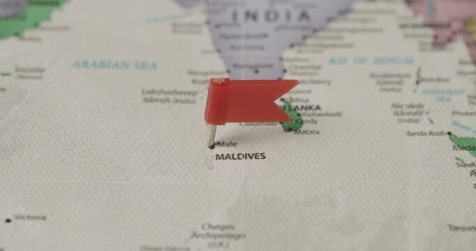 Red flag pin marking Male on a detailed world map, shallow depth of field highlighting the Maldives as a tropical travel and vacation destination in the Indian Ocean