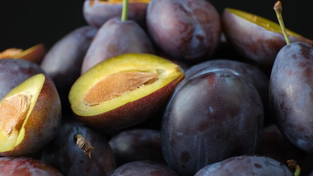 Halved ripe plums with exposed seeds turning slowly close up video