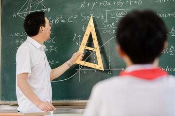 Teacher explaining mathematics with a set square at a blackboard © KhangSy