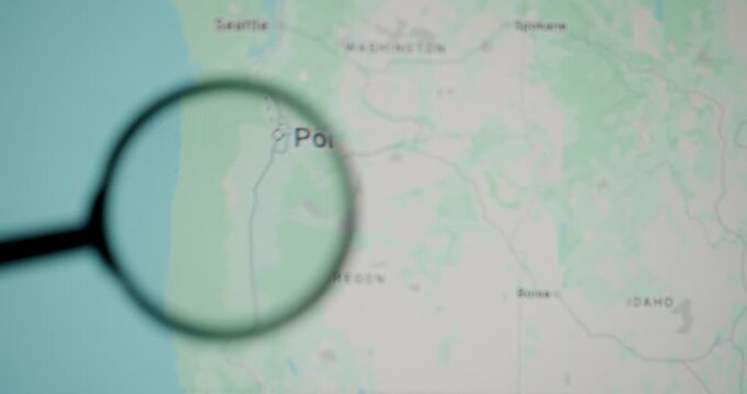 Detailed examination of a digital map focusing on the city of Portland in Oregon. With a hand holding a magnifying glass to inspect the location. Symbolizing research. Travel planning. Or geography