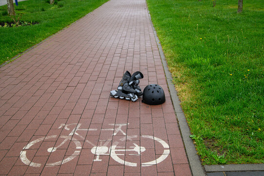 Inline skates and protective helmet on bicycle path in green park