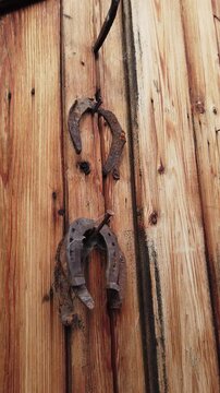 Old rusty horseshoes hanging on weathered wooden wall, vertical video 
