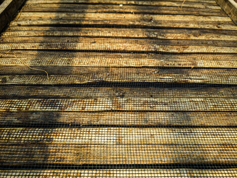 Close up perspective view of a wooden coffee drying bed with wire mesh for post-harvest processing