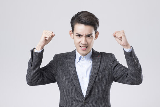 Angry young businessman clenching fists in frustration