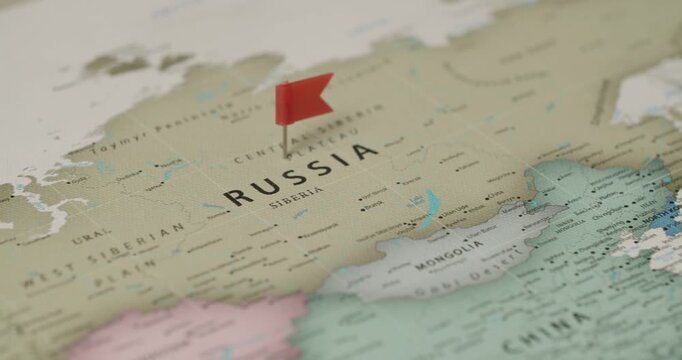 Close-up view of a red pin with a flag marking the country of Russia on a vintage-style world map, indicating a destination for travel, politics, or strategic planning