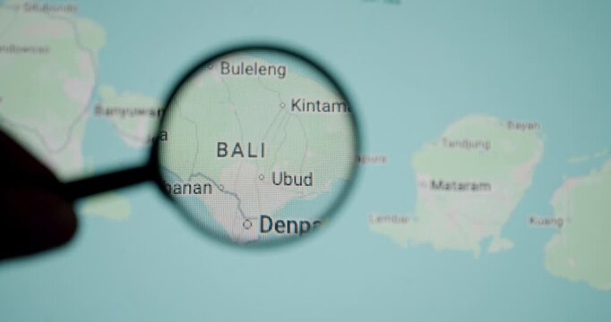 Close-up of a magnifying glass focusing on Bali, an Indonesian island, on a digital world map, representing travel planning, geography research, and tourism concepts for this popular destination