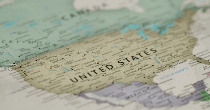 Macro view of a political map showing the United States of America. With a focus on its borders with Canada and Mexico. The camera slowly pans across the detailed geography and cities of the country