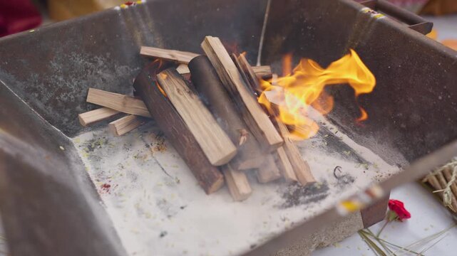 Wood logs burn in a square havan kund during a South Indian Karnataka wedding ritual, shot in soft slow motion.