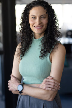 African American woman standing with arms crossed in office wearing ribbed mint top and smartwatch