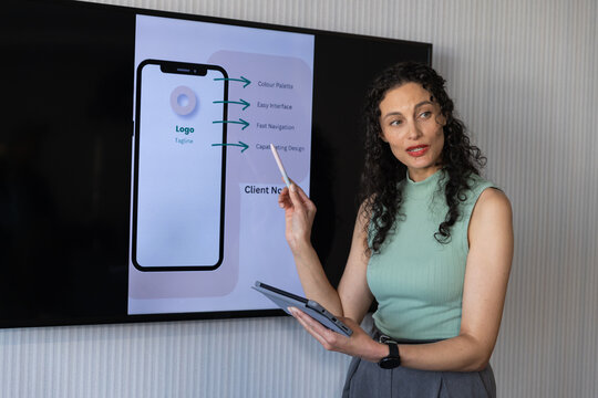 African American woman presenting app mockup on monitor in office, holding tablet, copy space