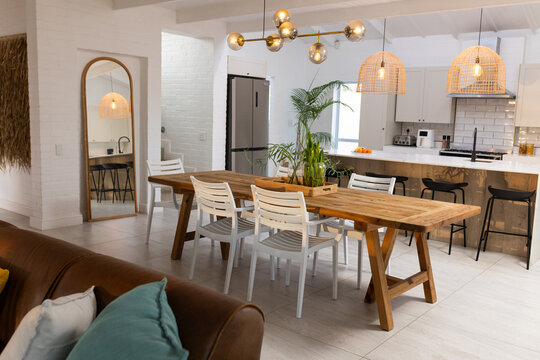 Long wooden trestle dining table is anchoring open-plan dining area with planter, gold chandelier