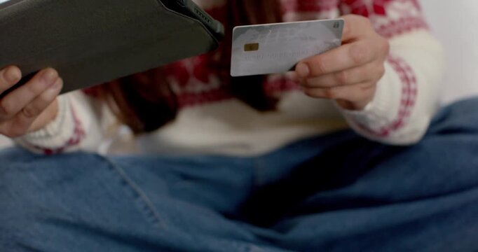 Woman spotting EMV chip card on bed, picking up card and checking tablet for payment