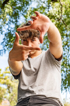 Joyful Gen Z male with attractive looks making a framing hand gesture with cool attitude