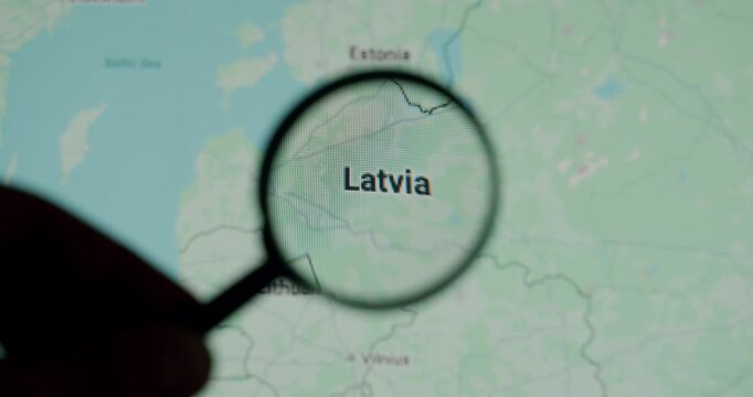 Person's hand holding a magnifying glass and exploring Latvia on an online map, zooming in on the country and its borders with Estonia and Lithuania for travel or study purposes