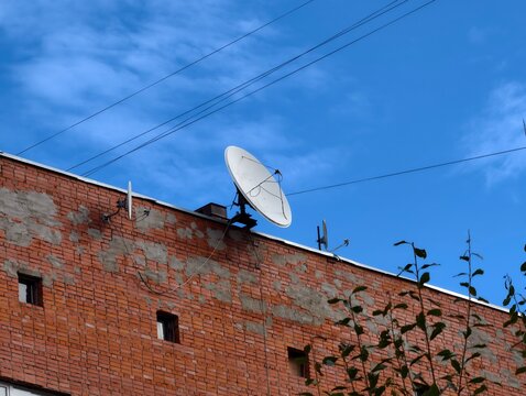 A satellite dish on top of a brick building, a common sight in many urban areas