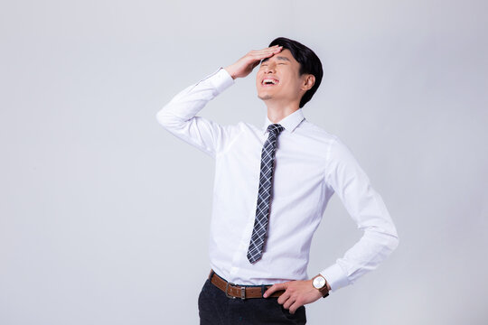 Stressed Asian Businessman Laughing and Holding His Forehead in Frustration