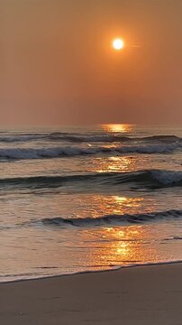A serene beach scene at sunset with gentle waves lapping at the shore. The sun casts a warm glow over the water, creating a peaceful atmosphere.