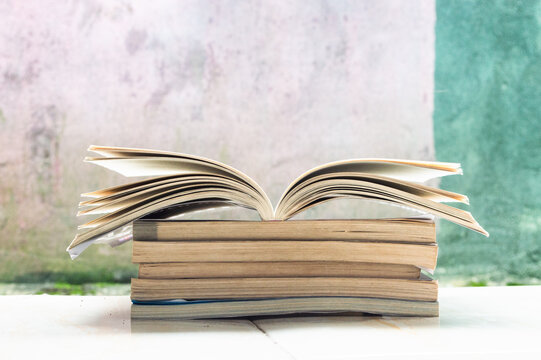 Open book on a stack of books with abstract background,