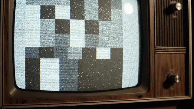 Vintage Television Screen Static - A close-up shot of an old television screen displaying static noise. The wooden casing of the television and its analog knobs are visible.