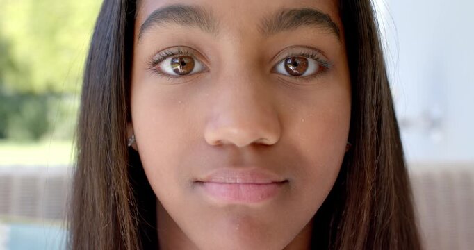 Teenage African American girl noticing camera, shifting eyes, smiling, laughing on porch with studs