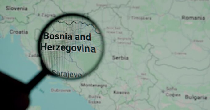 Inspection of Bosnia and Herzegovina on a paper map with a magnifying glass, focusing on the country and its capital, Sarajevo, for travel planning, geography studies, or political analysis