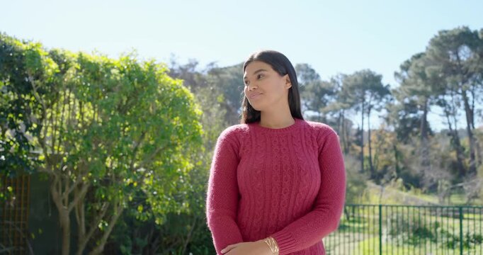 African American woman in fuchsia sweater turning and laughing with lens moving in, smiling in yard