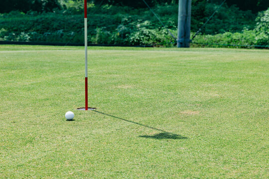 ゴルフ場のグリーン上に立つピンフラッグとボールの風景