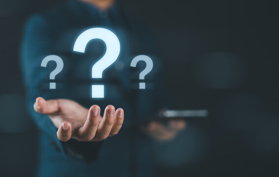 Businessman holding glowing question mark symbol representing problem solving uncertainty curiosity innovation decision making challenge and creative thinking concept in business and technology.
