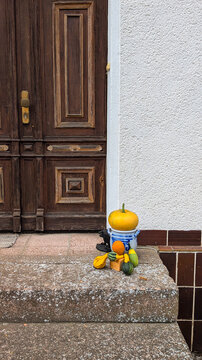 Halloween doorstep decor with decorative pumpkins and gourds on stone steps.