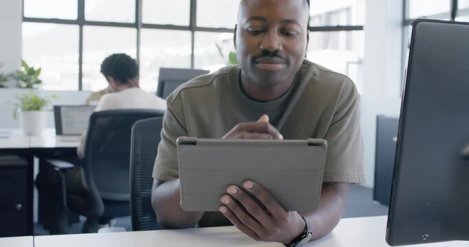 African American man reading tablet with folio case, tapping, thinking over work decision in office
