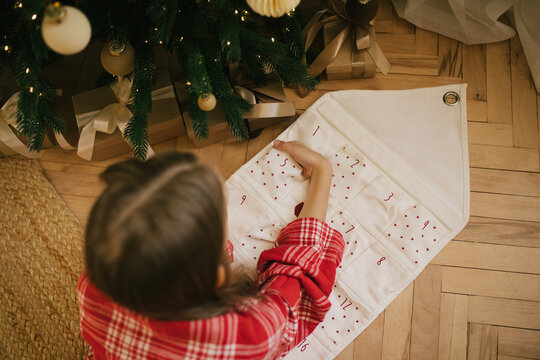 Cute 7-years old girl looking for a present in her Christmas advent calendar.