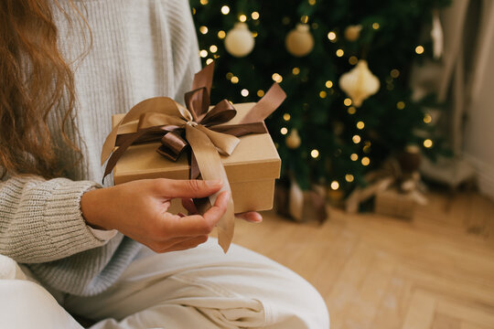 Young beautiful woman relaxing sitting under decorated Christmas tree.