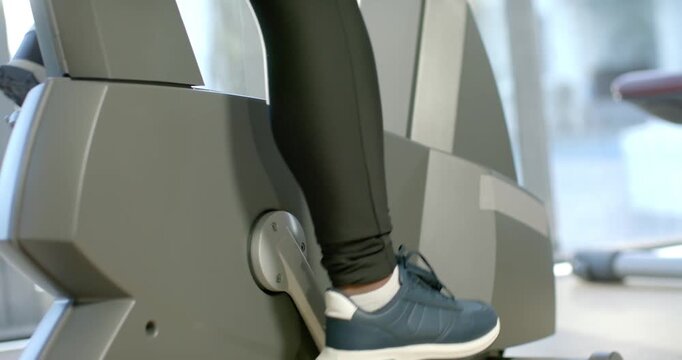 Foot wearing blue sneaker is pressing pedal as machine is starting, driving steady gym workout